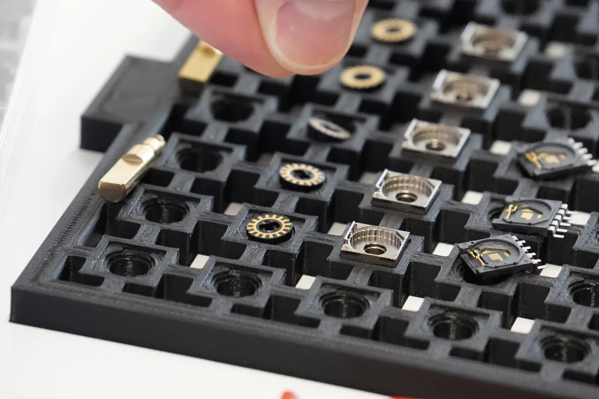 Eine schwarze Schale mit Teilen von Drehschaltern: Es sind runde Kunststoffplatten mit einem goldenen Kranz.